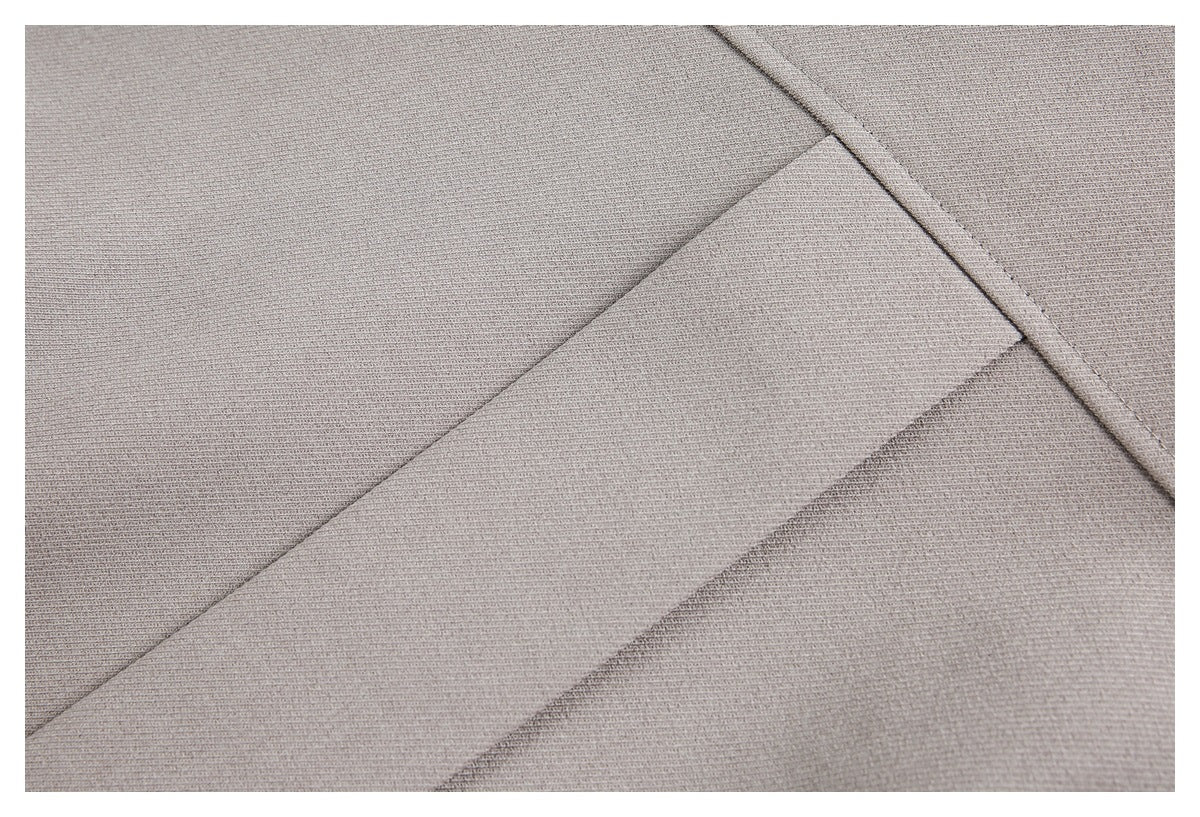 Close-up of taupe garment fabric showing overlapping panels and a stitched seam.