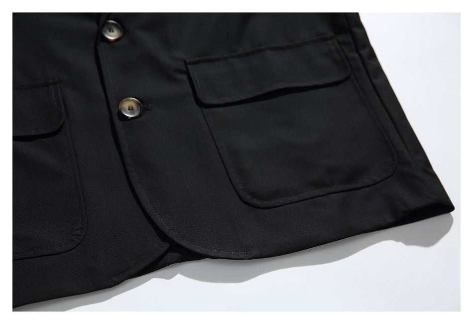 Close-up of a black blazer front with two buttons and large flap pockets.