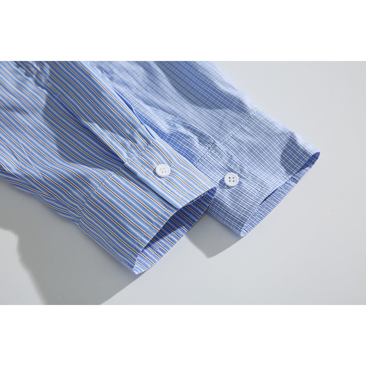 Close-up of two blue striped shirt cuffs with white buttons and contrasting stripe patterns.