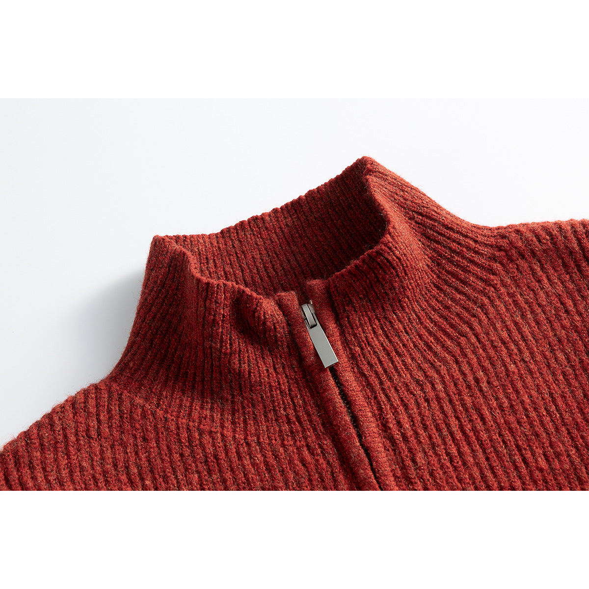 Close-up of a rust-red ribbed knit sweater’s high collar and partially zipped front.