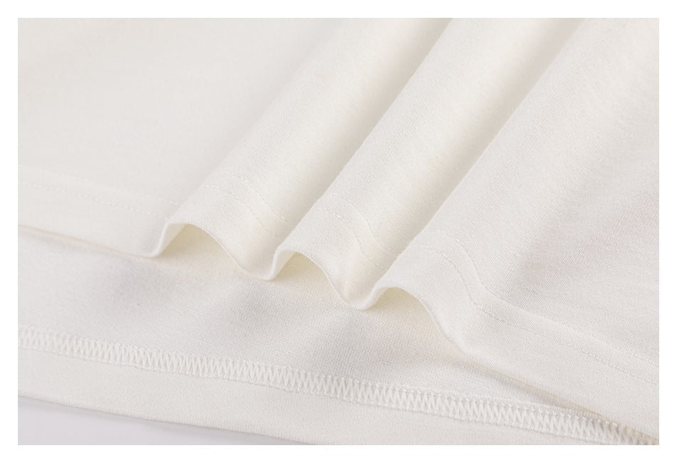 Close-up of the off-white shirt's folded hem and stitched edge.