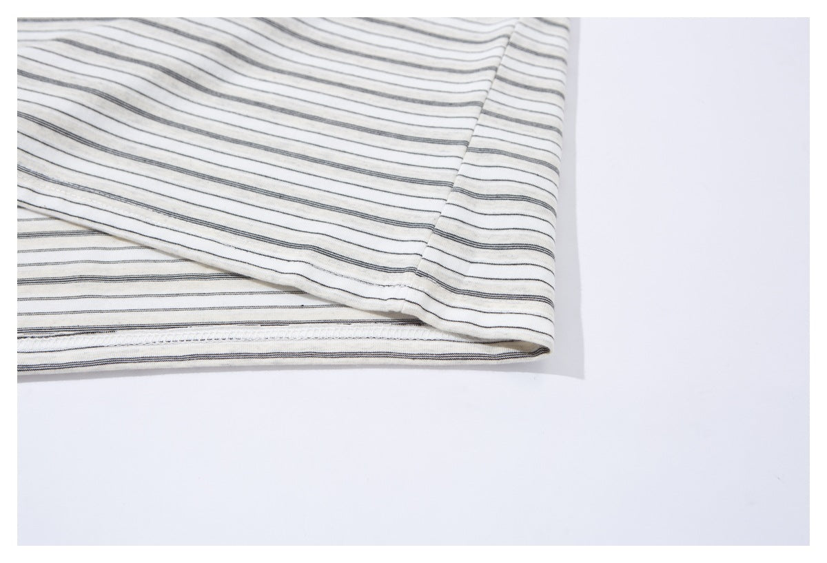 Close-up of the bottom hem and stitching on an ivory shirt with thin dark stripes.