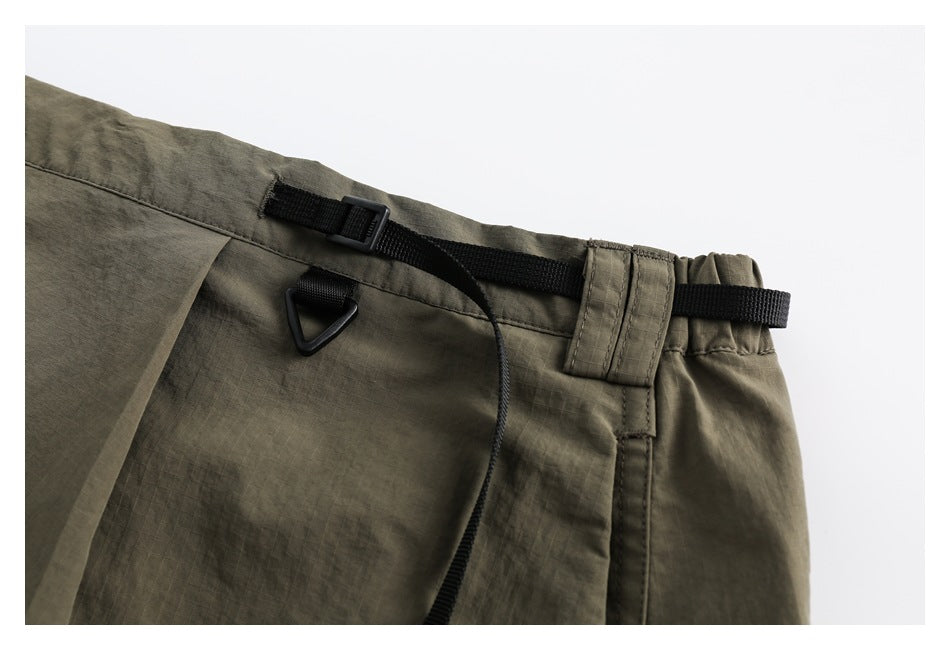 Close-up of the olive skirt waistband with a black adjustable webbing strap, buckle, and triangular loop.