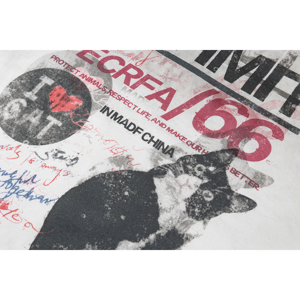Close-up of distressed red and black cat-themed lettering printed on an off-white T-shirt.