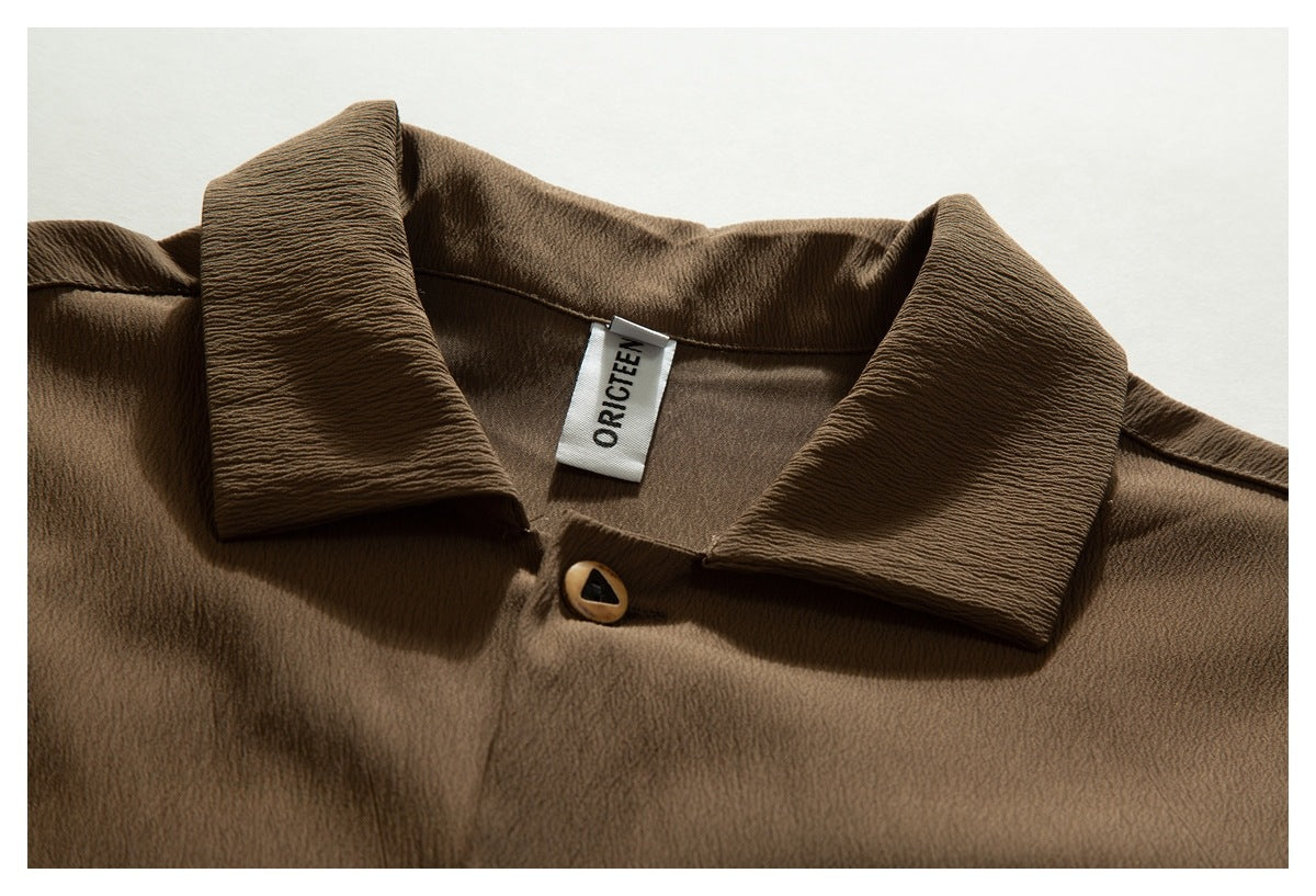 Close-up of a brown shirt collar, top button, and sewn neck label.