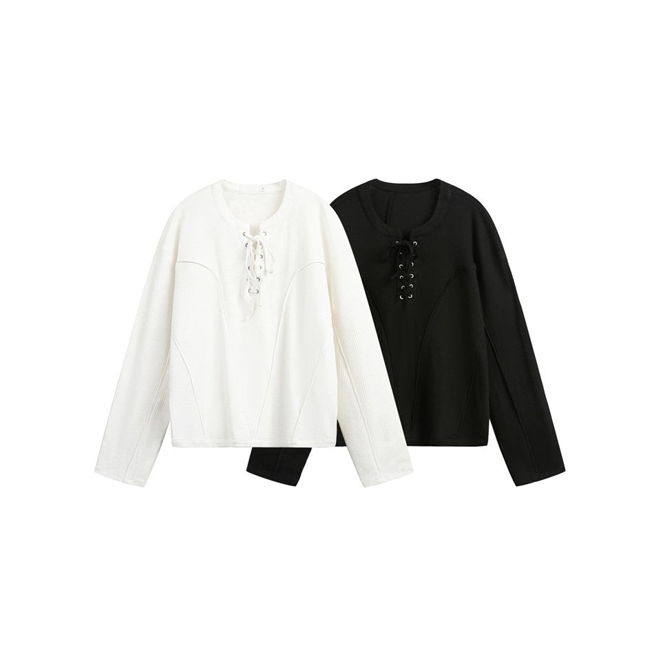 Ivory and black long-sleeve tops shown side by side, each with a lace-up neckline and curved seam details.
