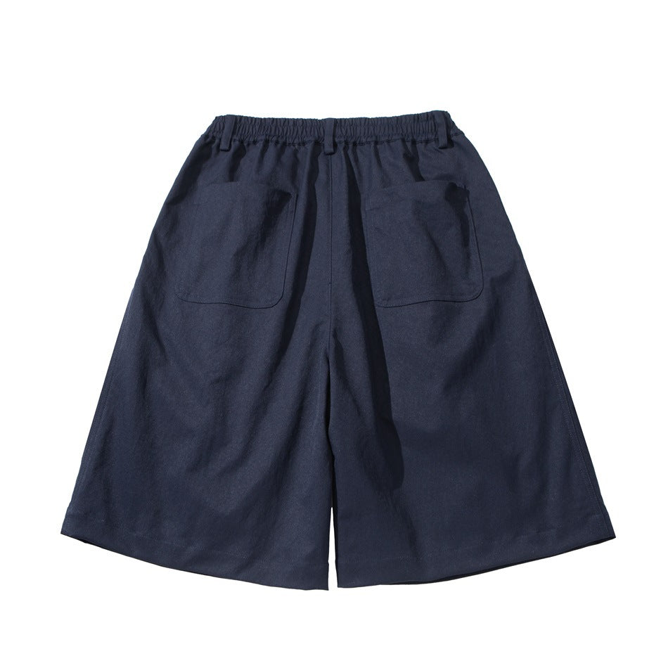 Back view of navy wide-leg shorts with an elastic waistband, belt loops and two patch pockets.