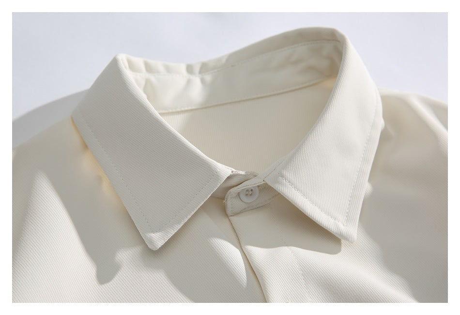 Close-up of the ivory shirt's pointed collar and top button.