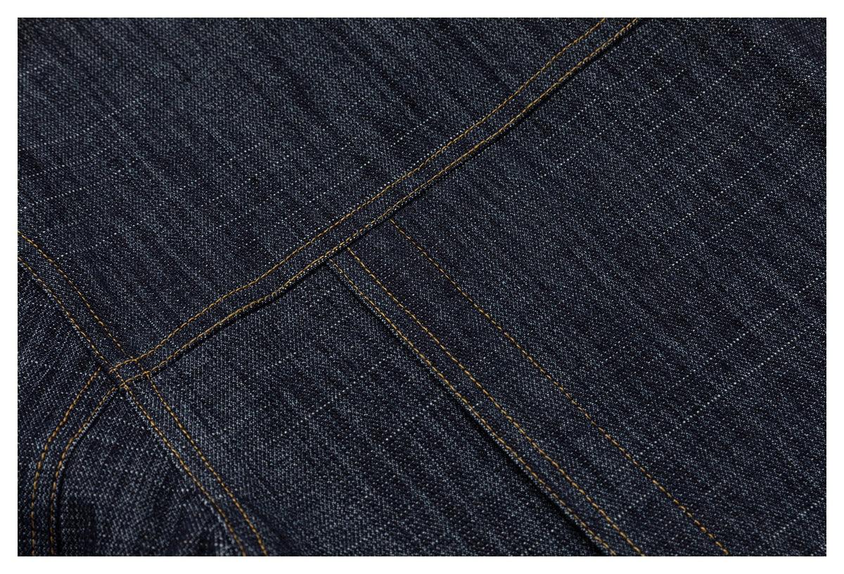 Close-up of dark indigo denim with contrasting golden-brown double stitching and intersecting seams.