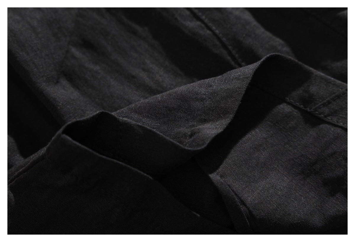 Close-up of a folded edge and stitching on black garment fabric.