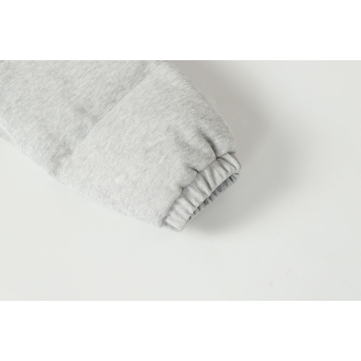 Close-up of a light gray heather jacket sleeve ending in a gathered elastic cuff.