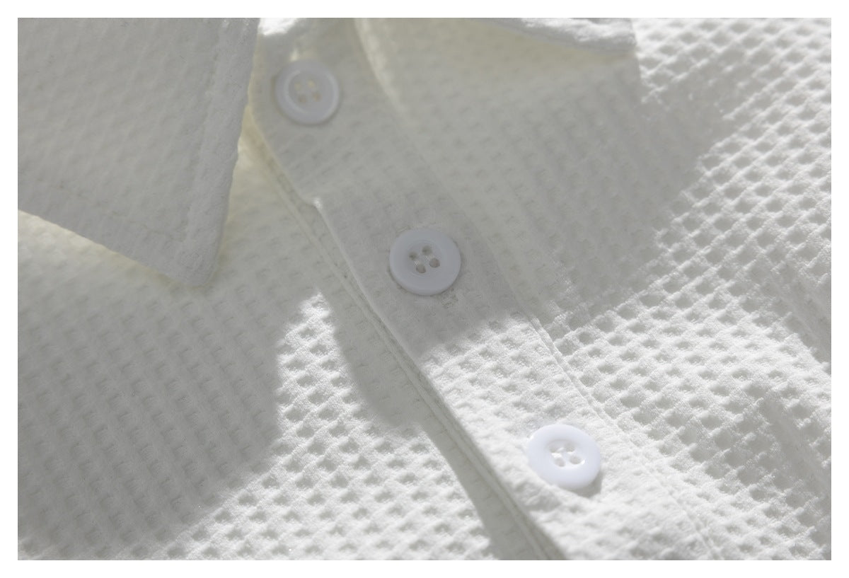 Close-up of a white button placket on textured fabric, with three white buttons.
