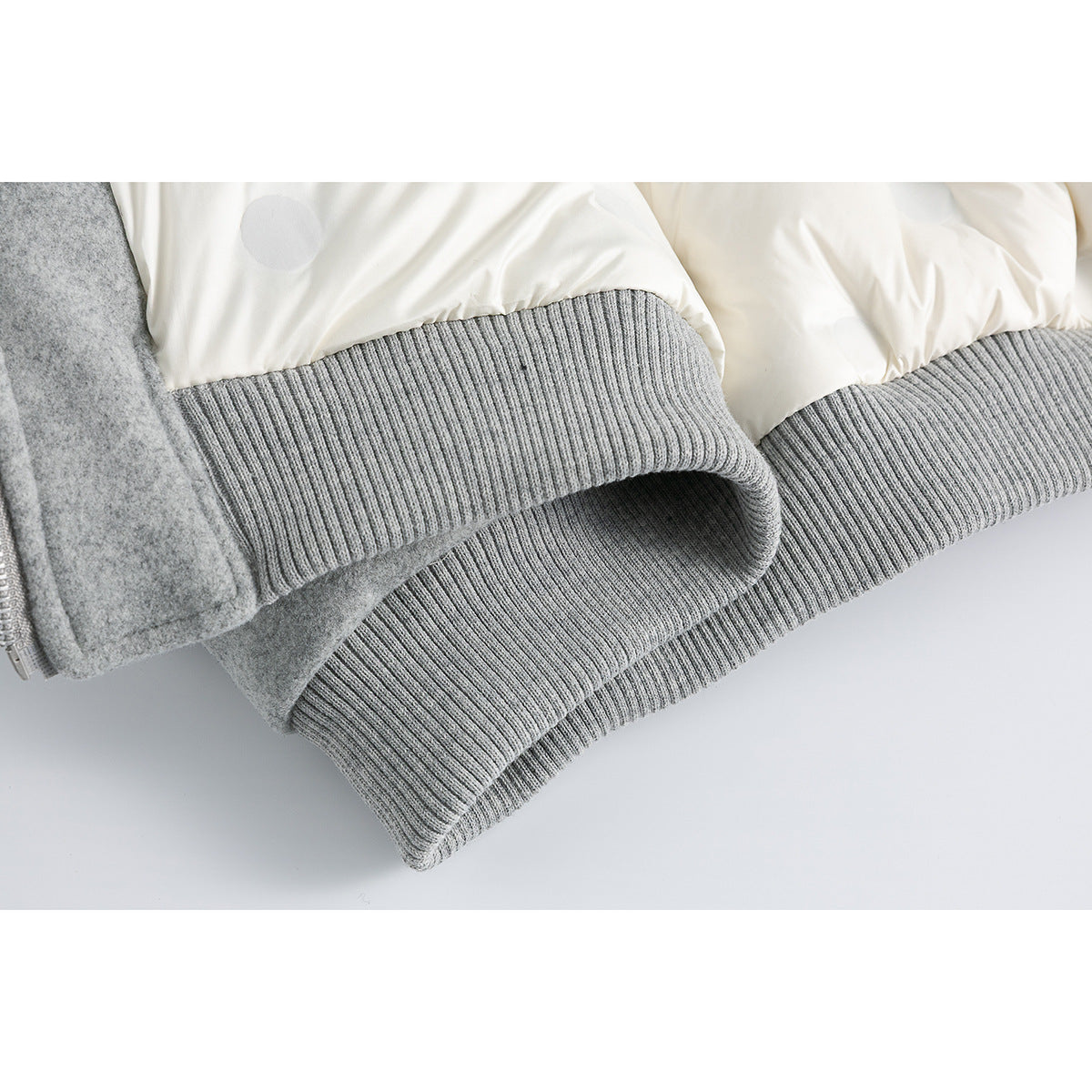 Close-up of a gray jacket's ribbed cuff and cream-colored quilted lining.