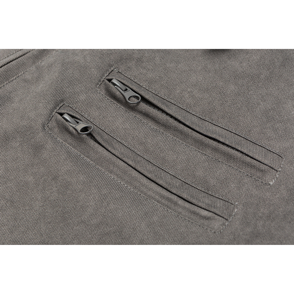 Close-up of two slim zip pockets on charcoal gray jacket fabric.