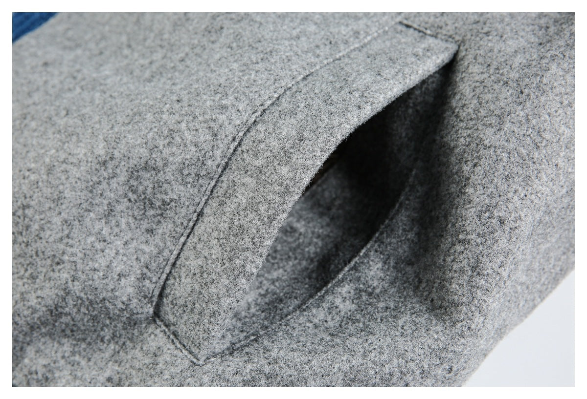 Close-up of a slanted welt pocket on gray jacket fabric.