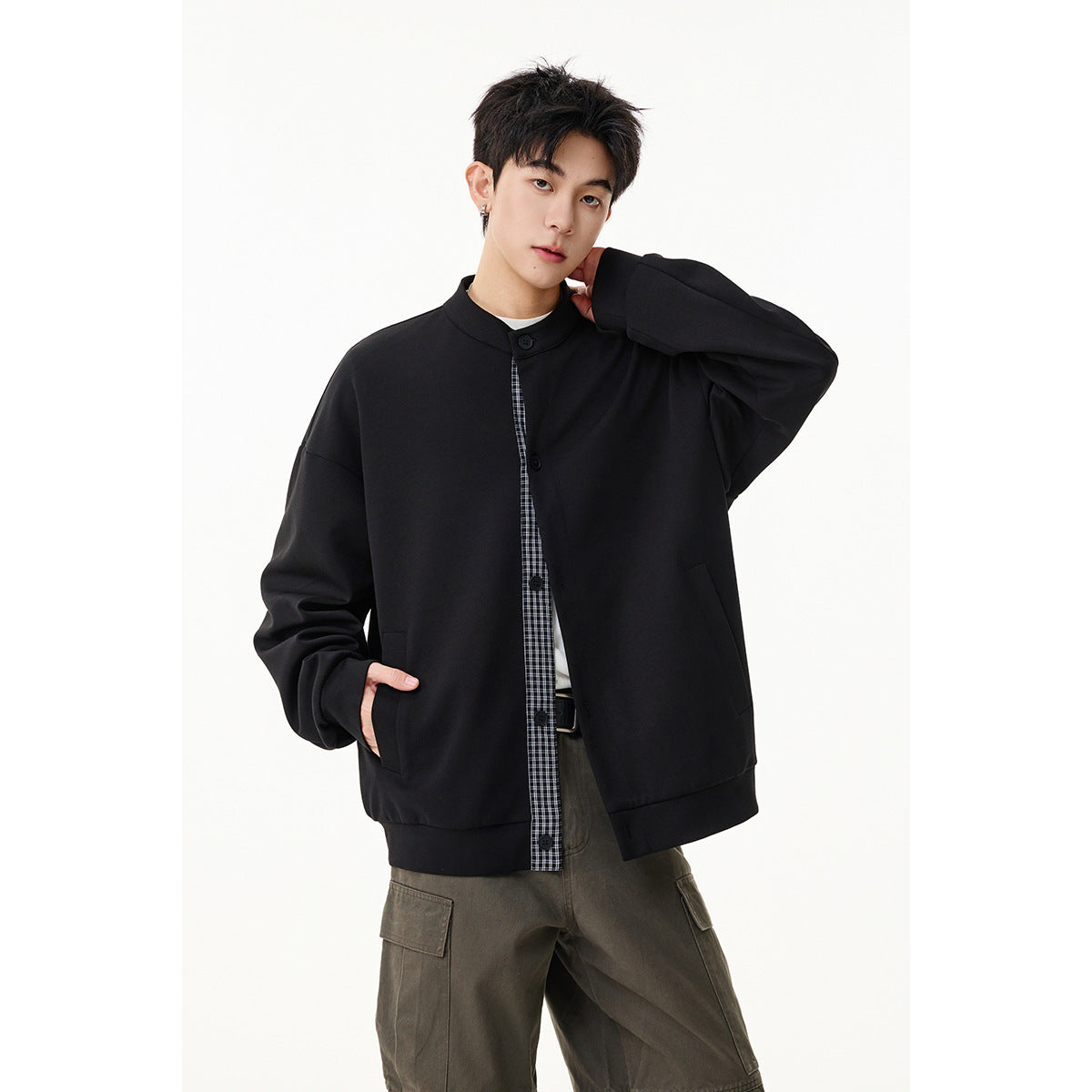 Model wearing an oversized black button-front jacket with a stand collar and plaid inset.