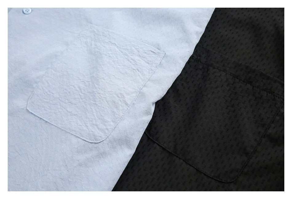 Close-up of light blue and black shirts showing their textured fabric and single chest pockets.