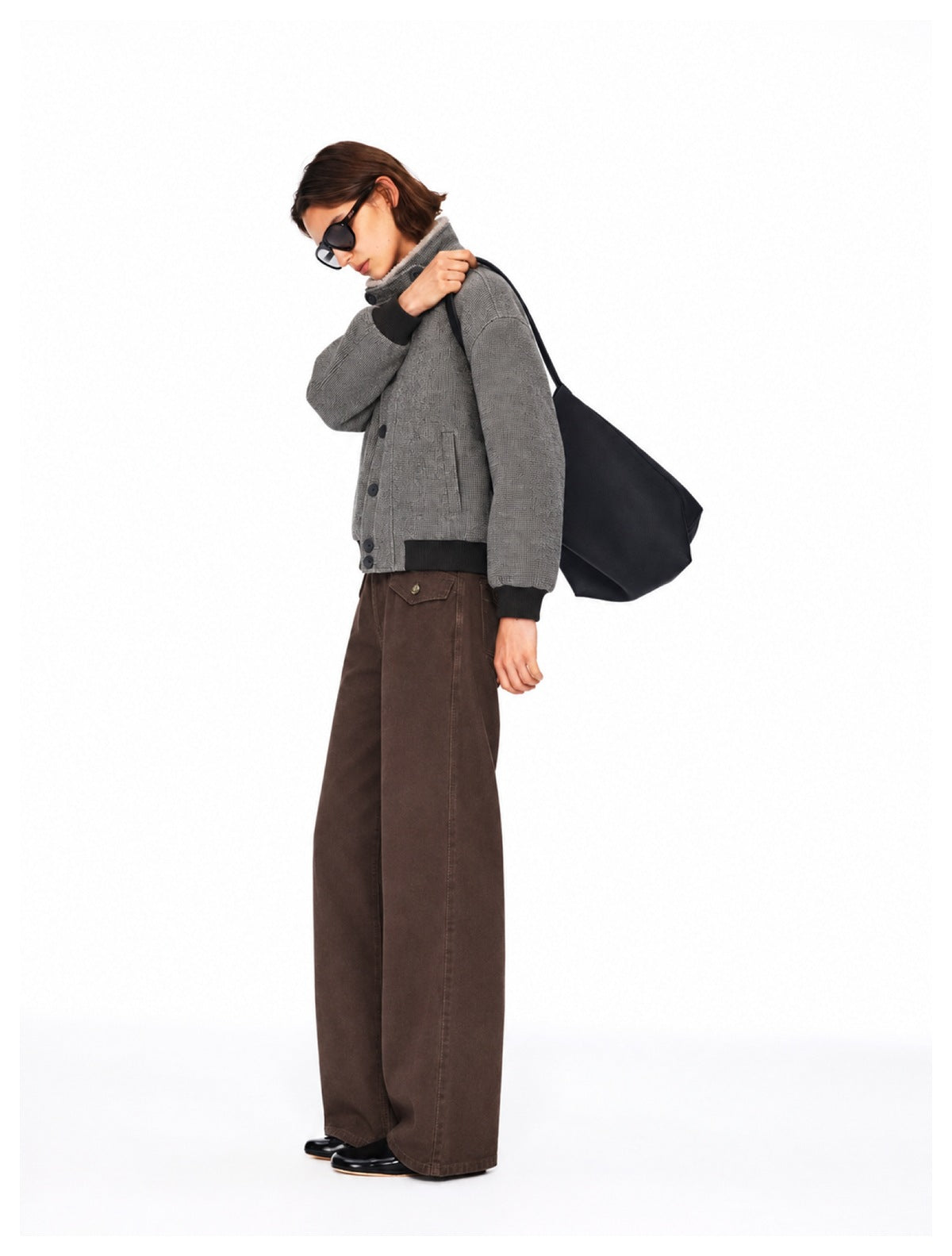 Side view showing the gray jacket's button front and black ribbed trim, paired with wide-leg brown pants.