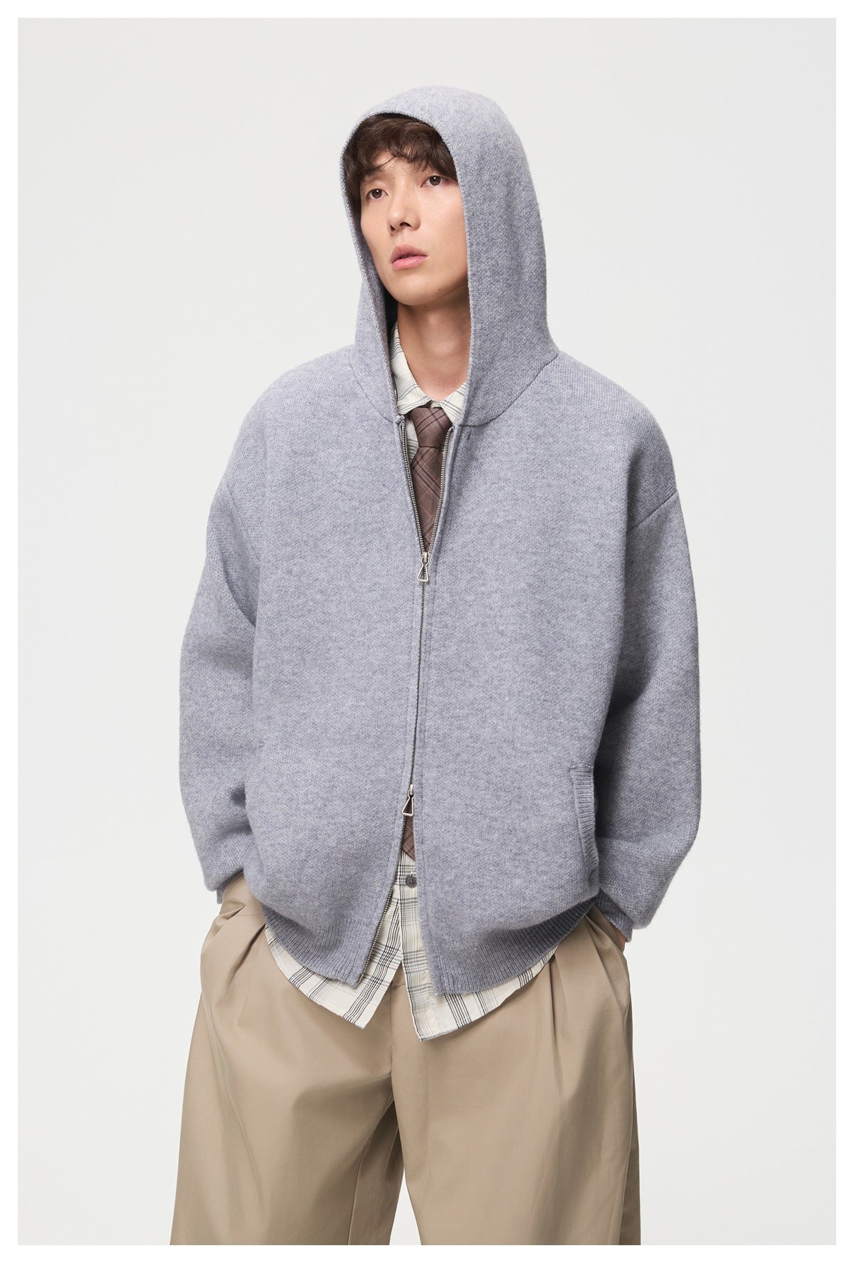 Model wearing a light gray zip-front knit jacket with the hood up and roomy sleeves.