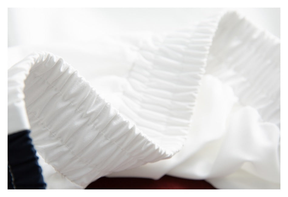 Close-up of gathered white fabric with a dark navy section at the edge.