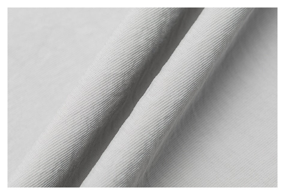Macro view of light gray fabric folded to show its fine, subtle ribbed texture.