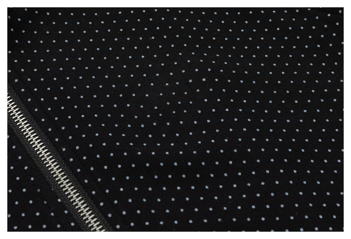 Close-up of black fabric with small gray dots and a diagonal silver zipper.