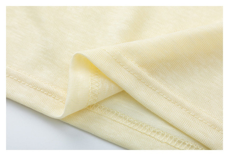 Close-up of pale yellow fabric folded to show its stitched hem and inner seam.