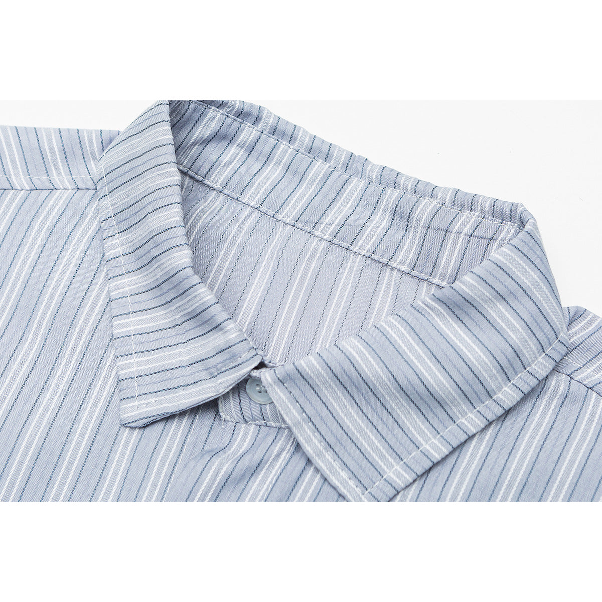 Close-up of a pointed collar and button on a light blue shirt with fine white and dark blue stripes.