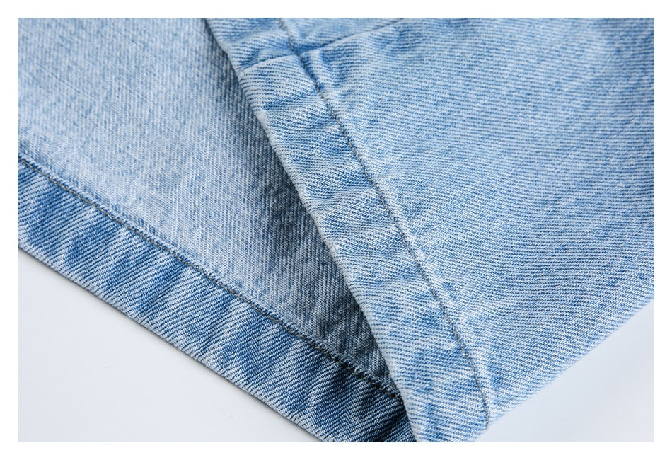 Close-up of a stitched seam and folded edge on light-wash blue jeans.
