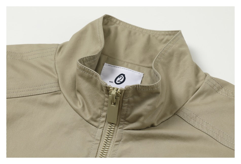 Close-up of a khaki jacket's stand collar, zipper, stitching, and inner size label.