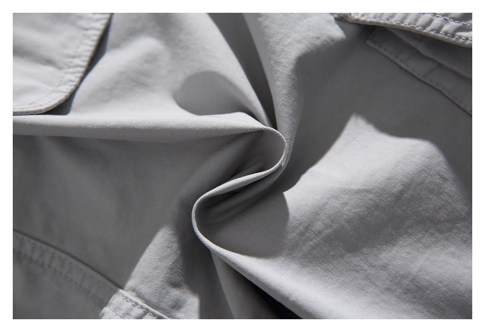 Close-up of light gray garment fabric, stitched edges, and a soft folded drape.