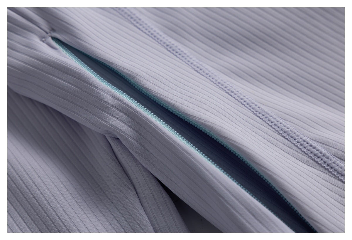Close-up of a diagonal aqua zipper opening against lavender ribbed fabric.