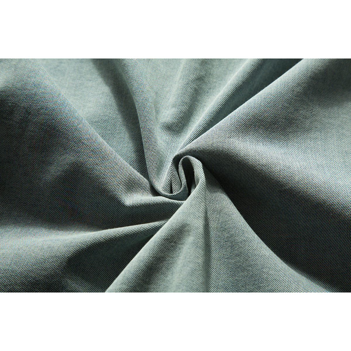 Close-up of light blue denim fabric gathered into soft folds, showing its diagonal weave.