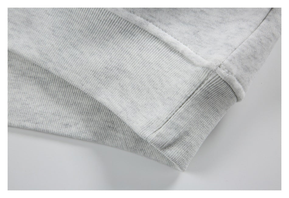 Close-up of a light gray heather sweatshirt hem with a ribbed band and visible seam.