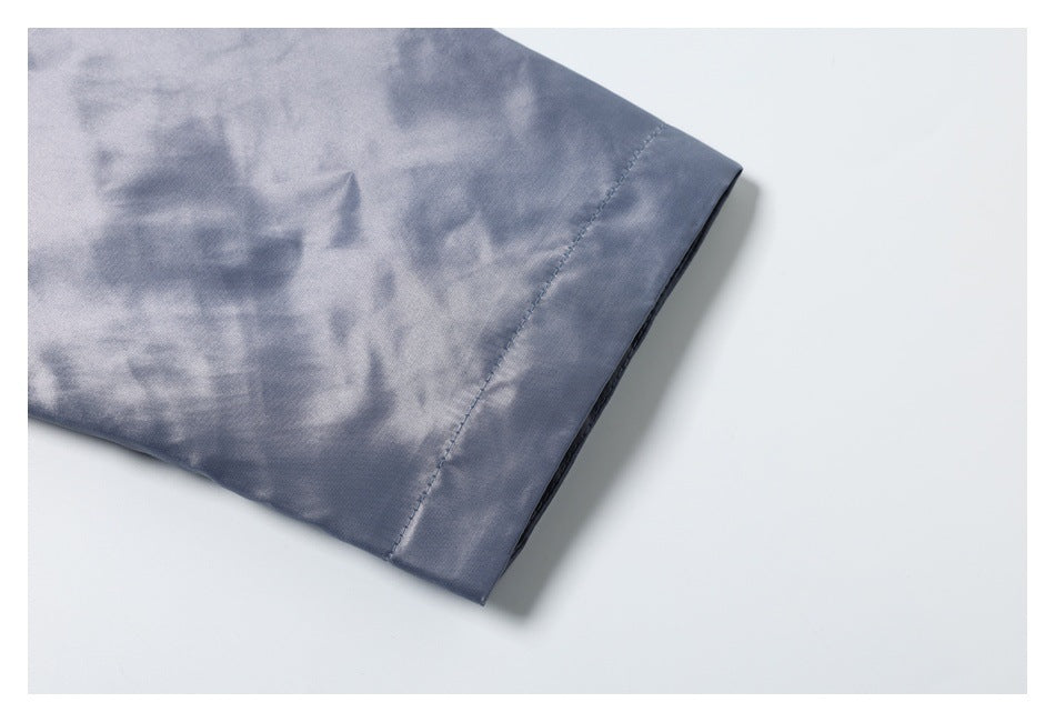 Close-up of a stitched sleeve hem on slate-blue fabric.