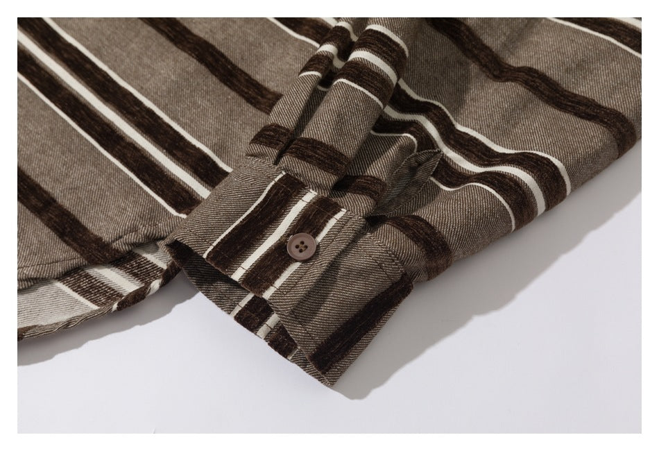 Close-up of a buttoned cuff and sleeve seam on striped taupe-brown fabric.
