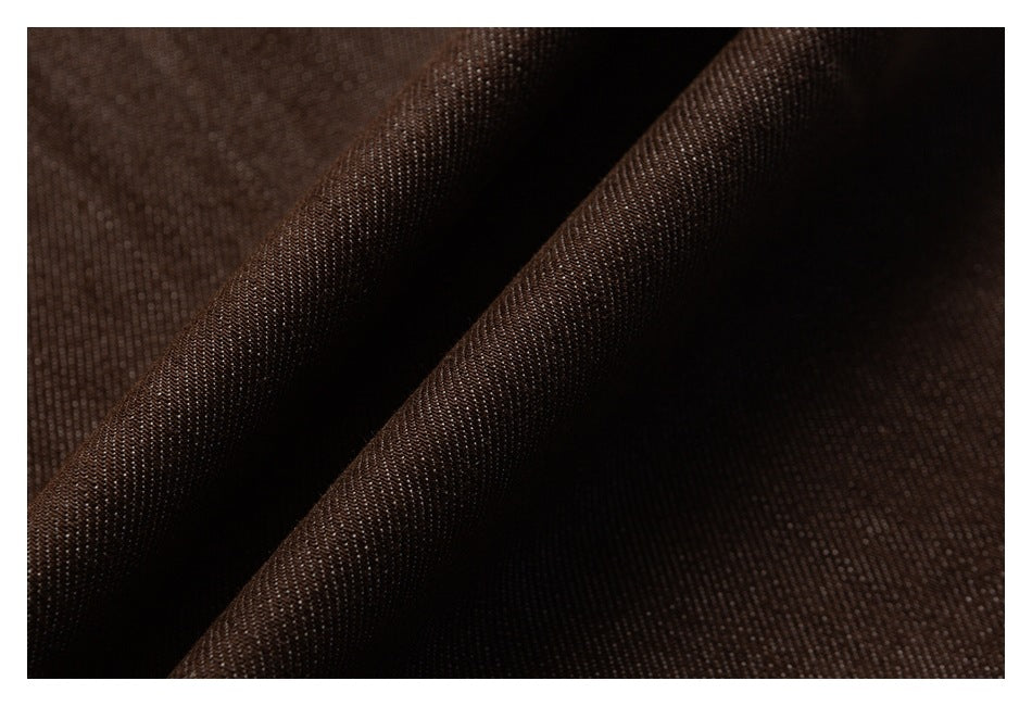 Close-up of dark brown fabric folded into soft ridges, showing its fine surface texture.