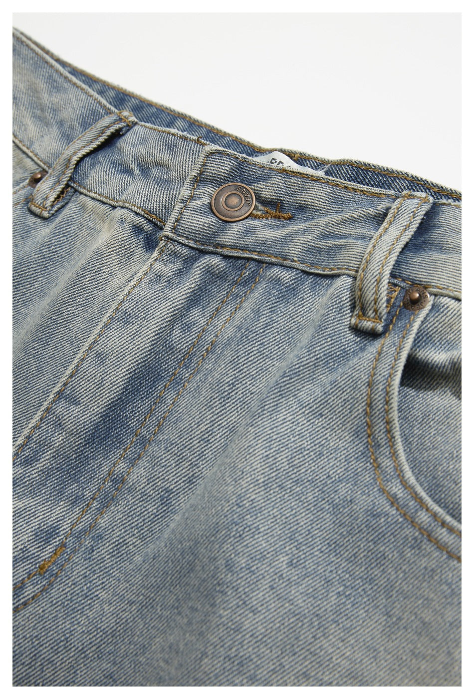 Close-up of the light blue jeans waistband, metal button, belt loop and front pocket seam.