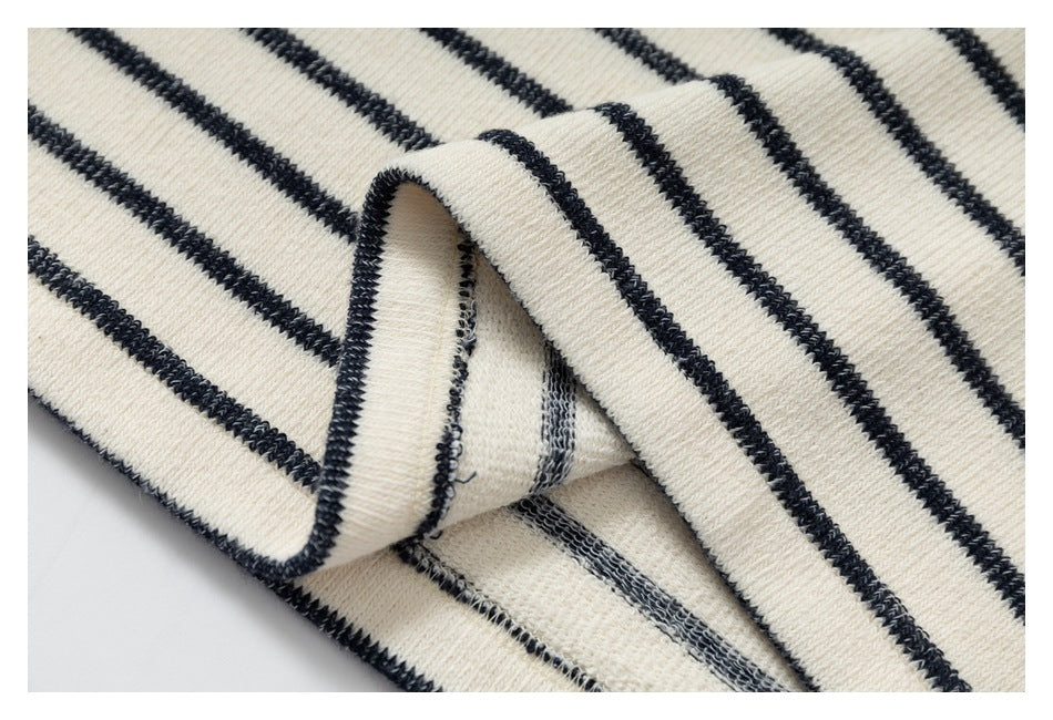 Close-up of folded cream-and-black striped knit fabric, showing the reverse side and overlocked seam.