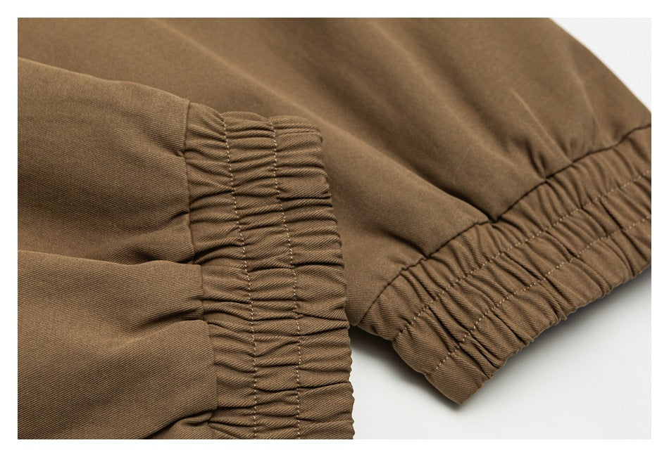 Close-up of brown garment fabric with gathered elastic trim and visible stitching.