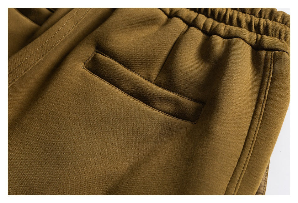 Close-up of olive-brown pants showing an elastic waist and a slanted side pocket.