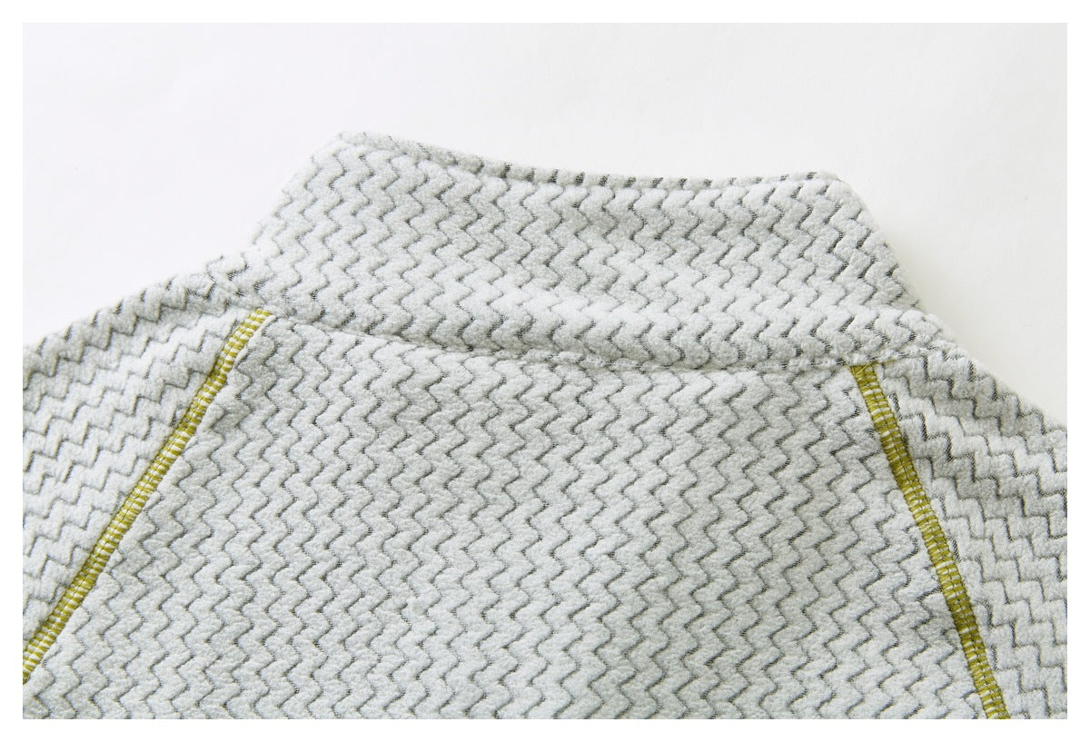 Close-up of a curved panel seam with yellow stitching on a light gray zigzag-patterned garment.