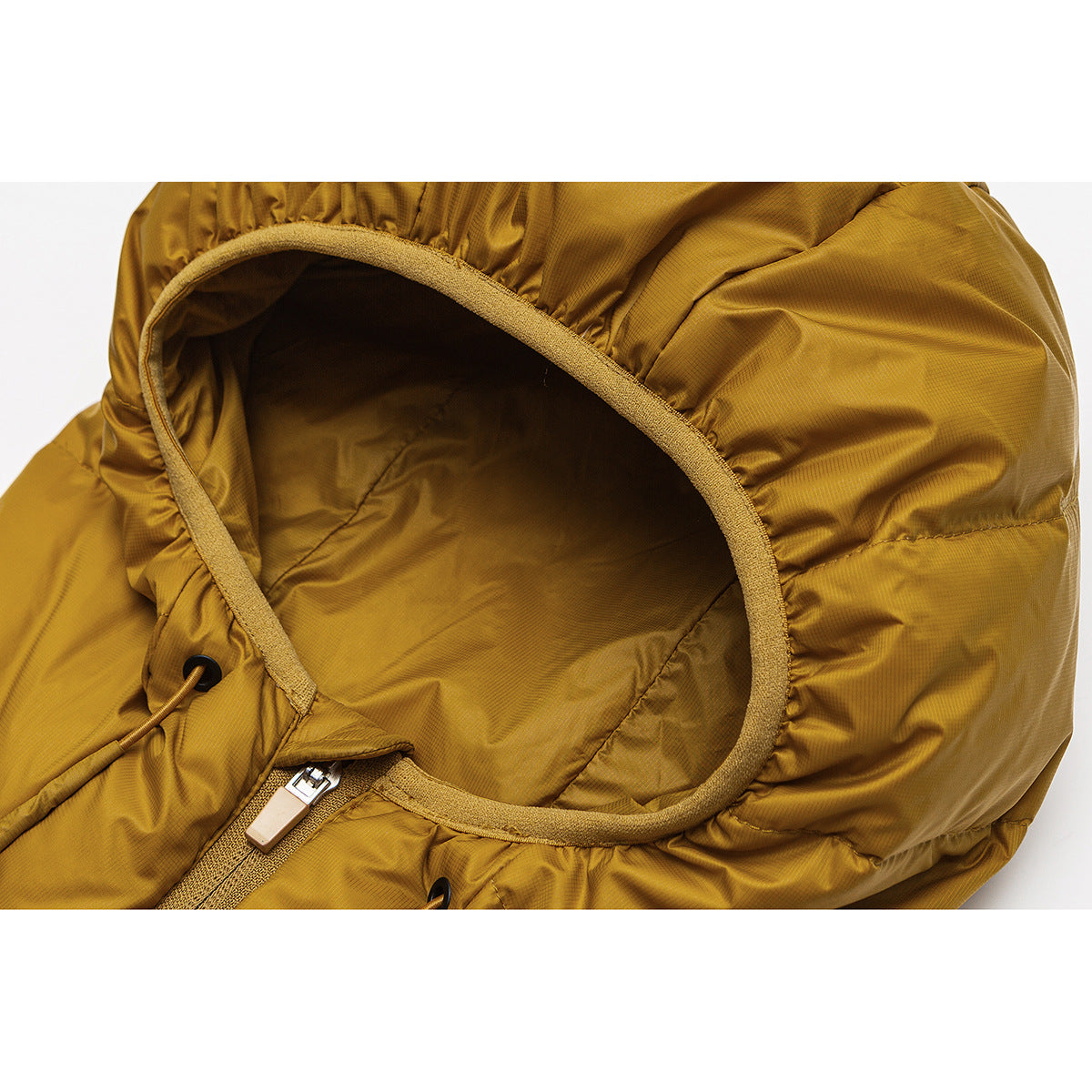 Close-up of a mustard hooded jacket showing the lined hood opening, drawcord, and zipper pull.