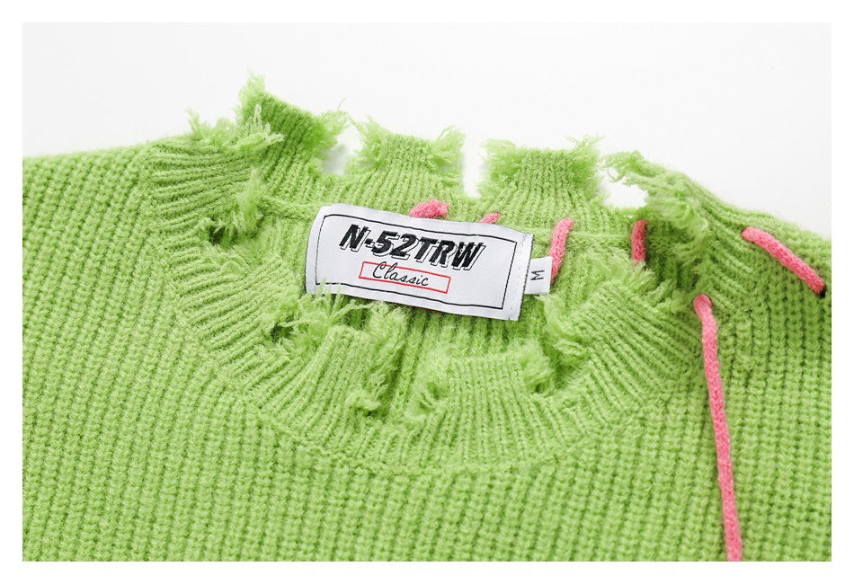 Close-up of the green sweater's distressed neckline, pink stitching, and sewn label.