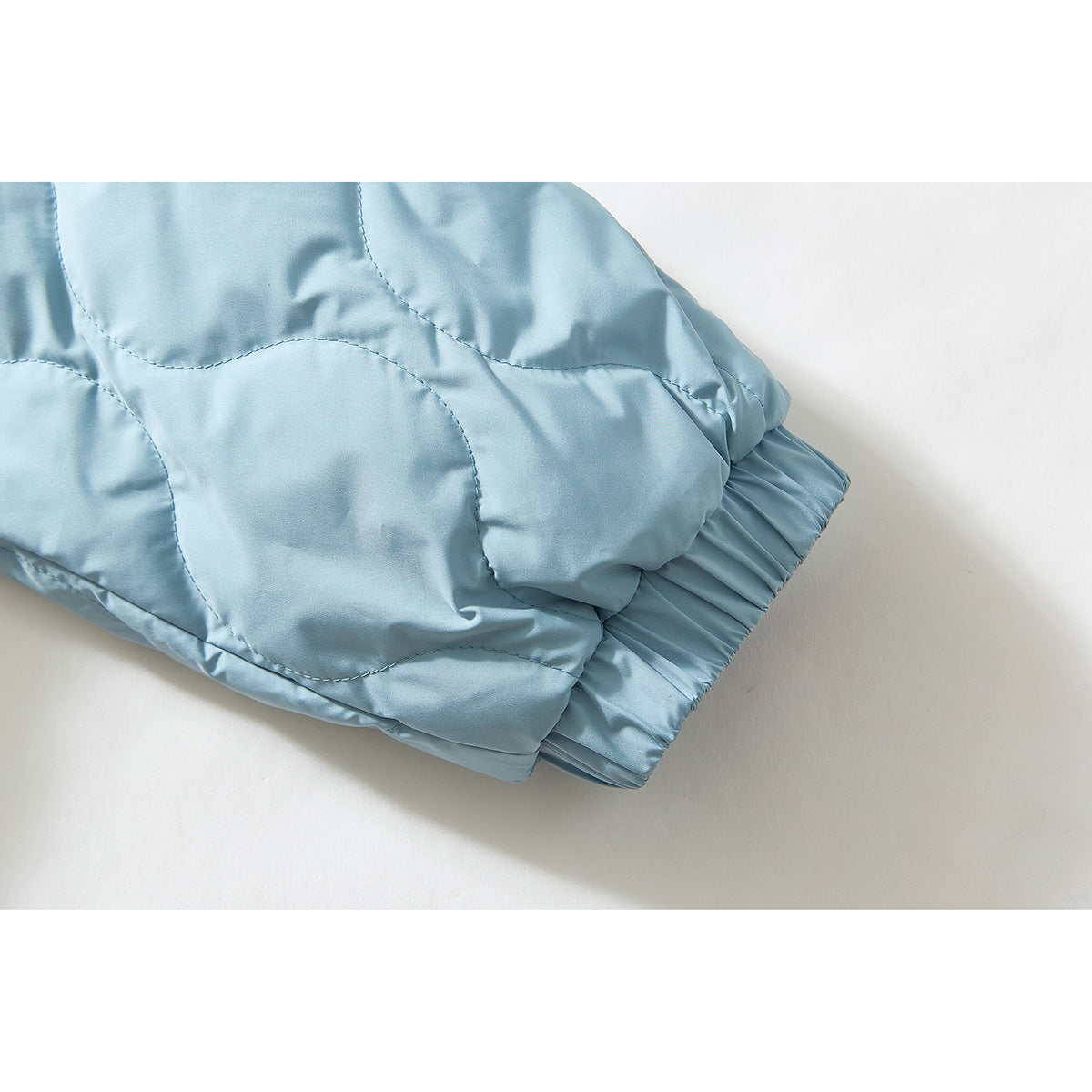 Close-up of a pale blue quilted jacket sleeve ending in a gathered elastic cuff.
