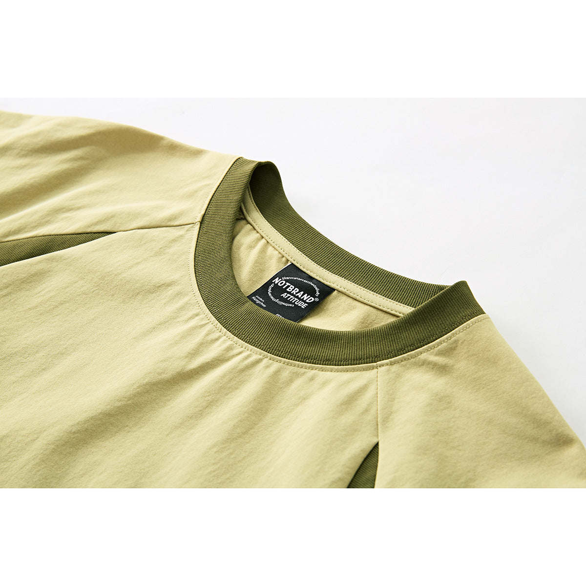 Close-up of a pale yellow-green T-shirt neckline with a dark olive ribbed collar and visible inner neck label.