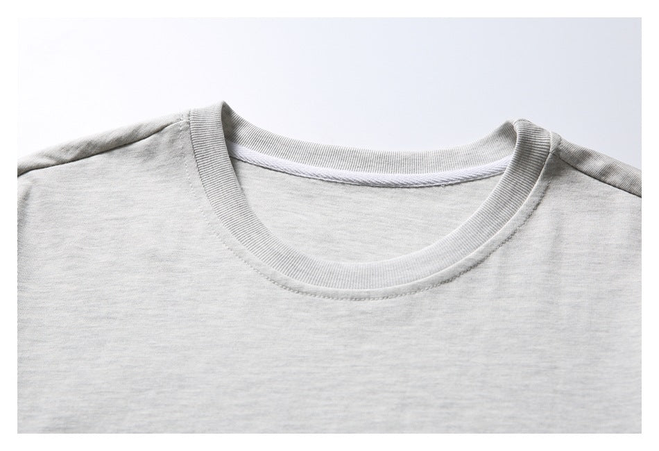 Close-up of a light gray melange T-shirt's ribbed crew neckline and shoulder seams.