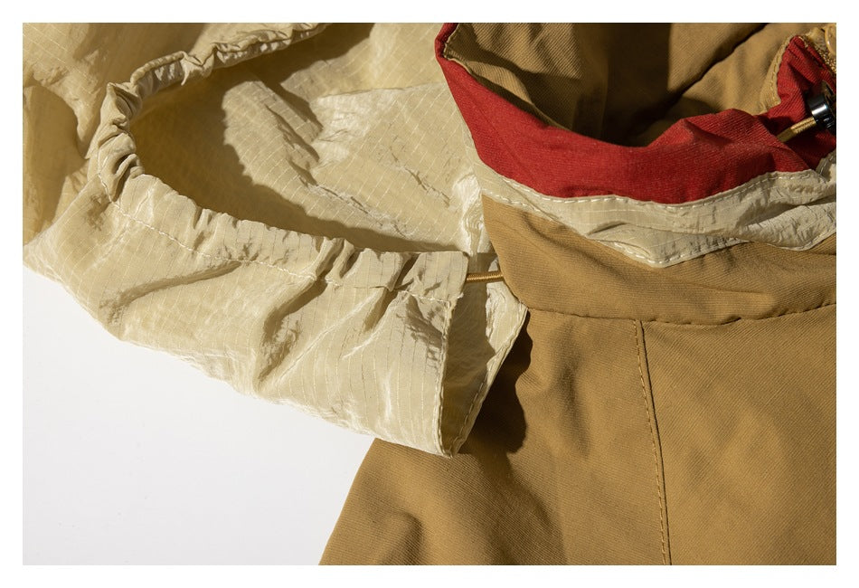 Close-up of the tan jacket’s cream hood lining, red collar trim, and seams.