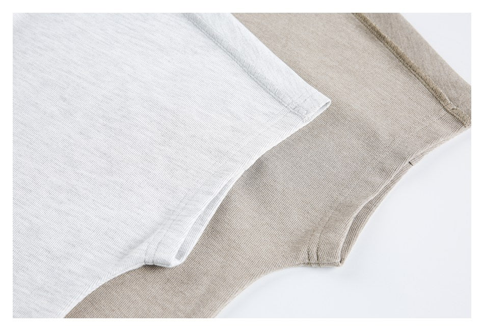 Close-up of overlapping white and taupe knit fabric panels with curved stitched edges.