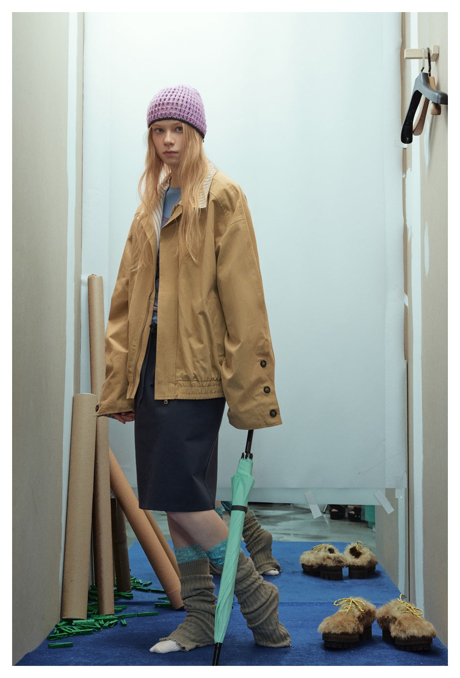 Model in oversized khaki jacket with striped collar, button sleeve tabs and elastic hem, side three-quarter view